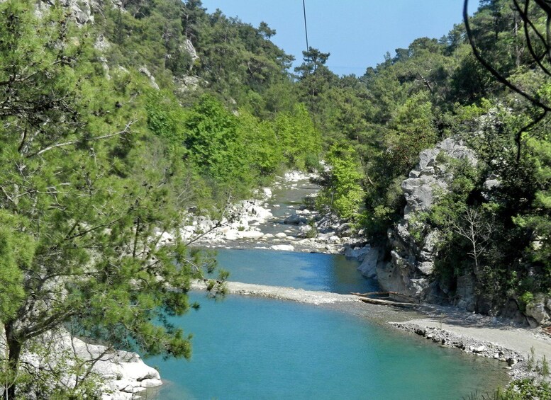 A river flowing through a mountainous area with dense greenery and rocky terrain. 3