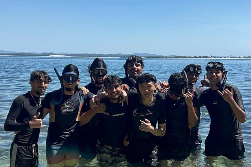 Un grupo de personas con trajes de neopreno posando junto al agua. 2