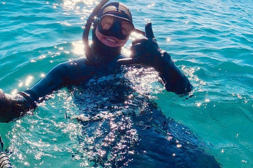 Una persona con traje de neopreno y equipo de snorkel nada en aguas azules y cristalinas. 3