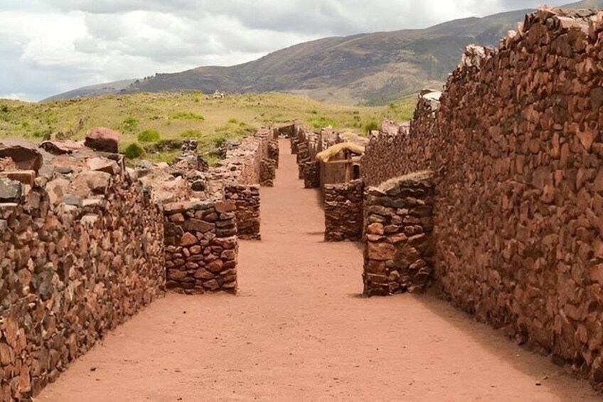 A stone pathway leading through an ancient stone structure with a mountainous backdrop. 1