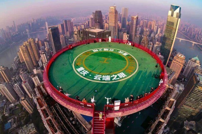 A stadium with a green field and red seating, surrounded by high-rise buildings. 1