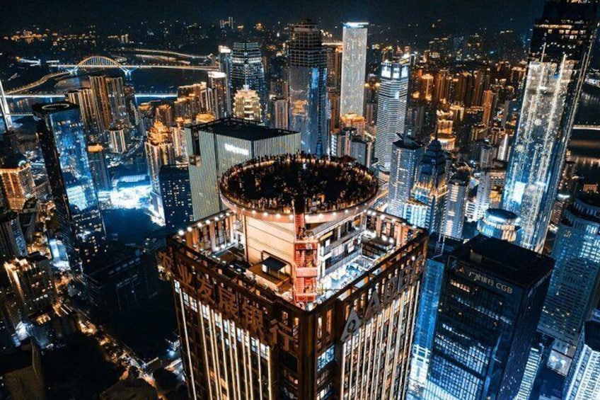 A cityscape at night with illuminated skyscrapers and a prominent circular building with a rooftop. 5