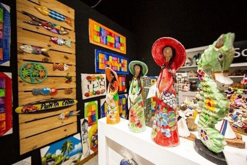A display of colorful, handcrafted figures with hats, set against a backdrop of various decorative items and a wooden wall with colorful patterns. 5