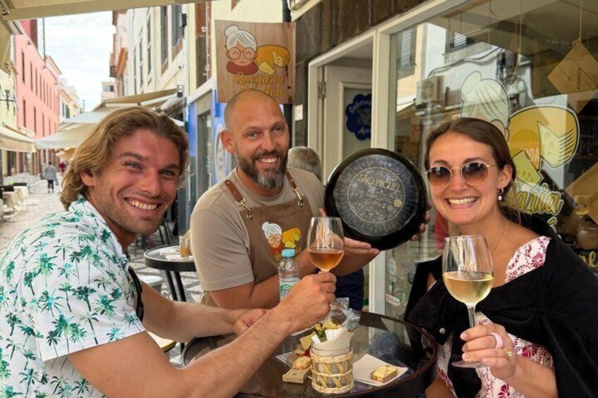Three people toasting with wine glasses at an outdoor café with a street view in the background. 3