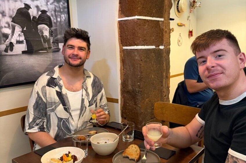 Two people sitting at a table with food and drinks. 5