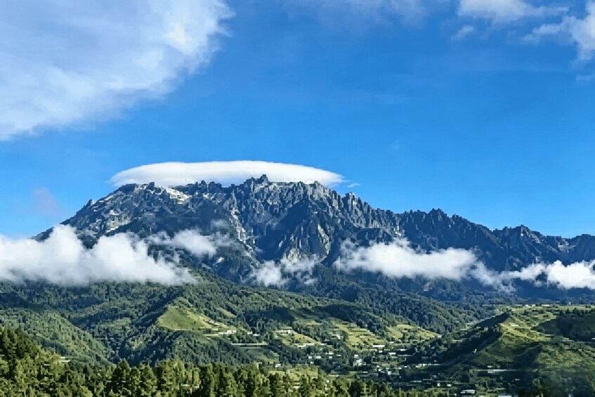 A mountain range with a prominent peak, lush green valleys, and scattered settlements. 1
