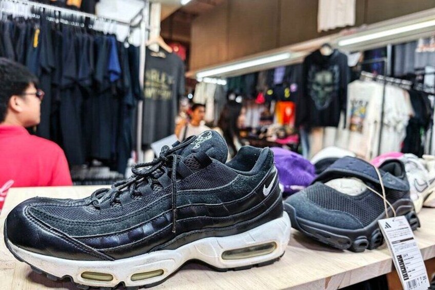 A sneaker display in a store with various clothing items in the background. 4