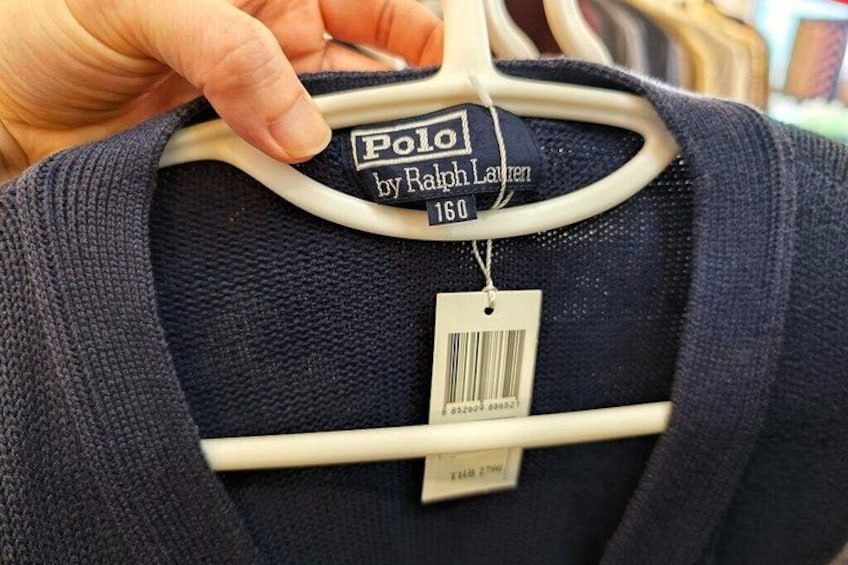 A dark blue polo shirt on a hanger with a tag. 5