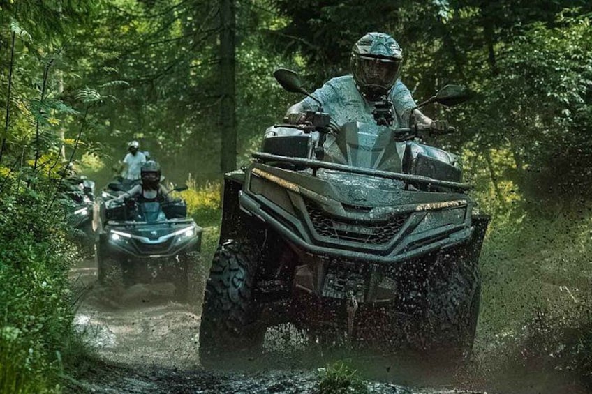 Two all-terrain vehicles on a muddy path in a forest. 1
