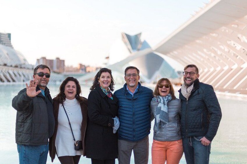 A group of people standing in front of a modern architectural structure with a curved design. 1