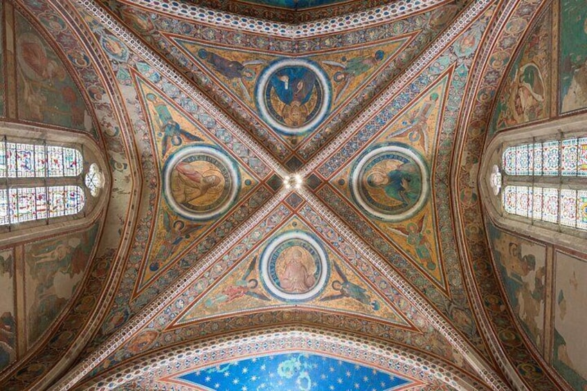 A detailed ceiling with geometric patterns and circular designs, featuring stained glass windows. 5