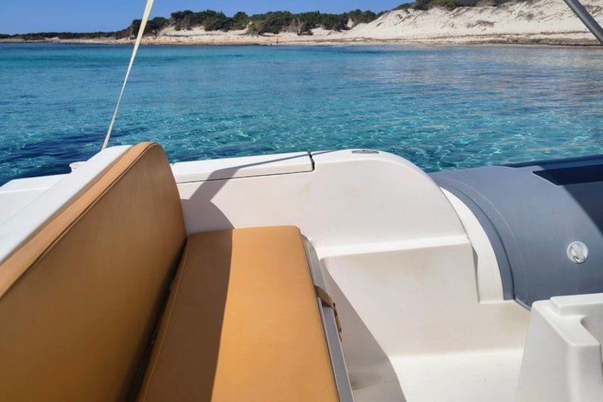 A boat's interior with a cushioned seat and a steering wheel. 2
