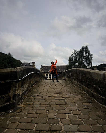 A stone bridge with a person in an orange jacket walking towards the end. 3