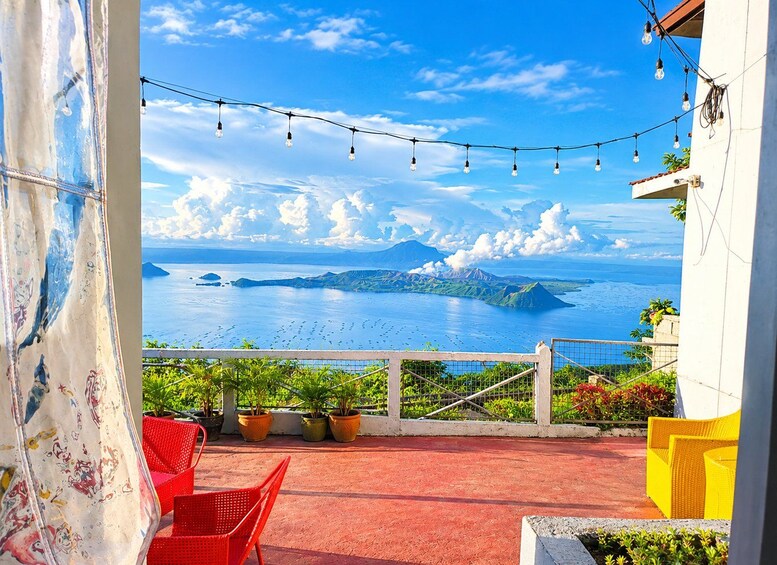 A balcony with red chairs, potted plants, and a view of the ocean and islands. 4