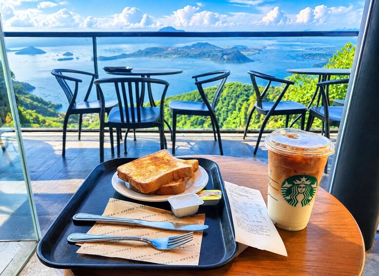 A tray with toast, a Starbucks iced coffee, and a menu on a table with a view of the ocean. 5