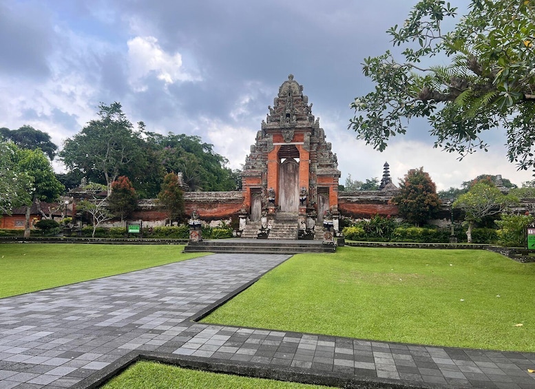 A temple with a central tower, surrounded by well-maintained grass and a paved walkway. 2