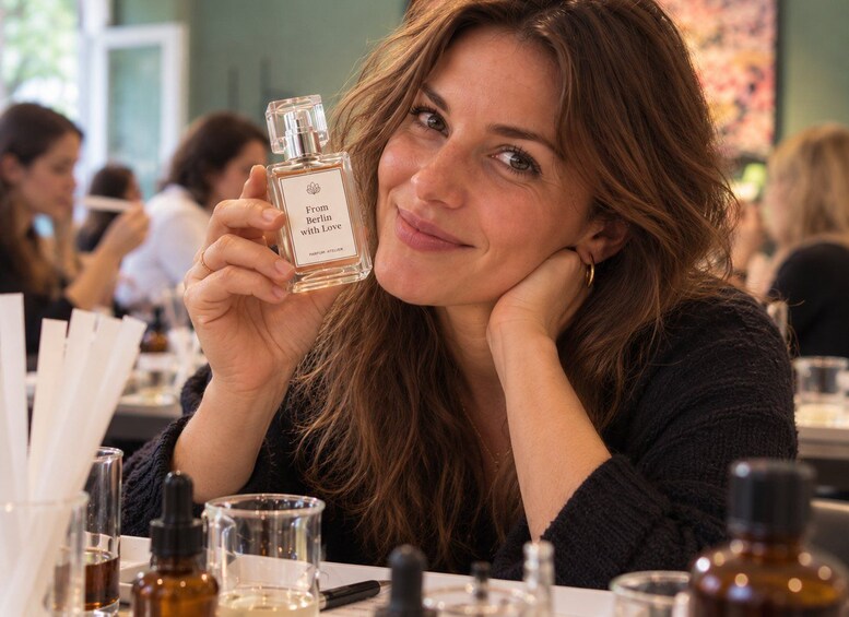 A person holding a perfume bottle with the label 'From Berlin with Love'. 1