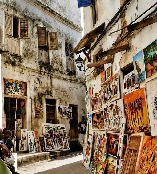 A street with a building displaying various paintings. 5