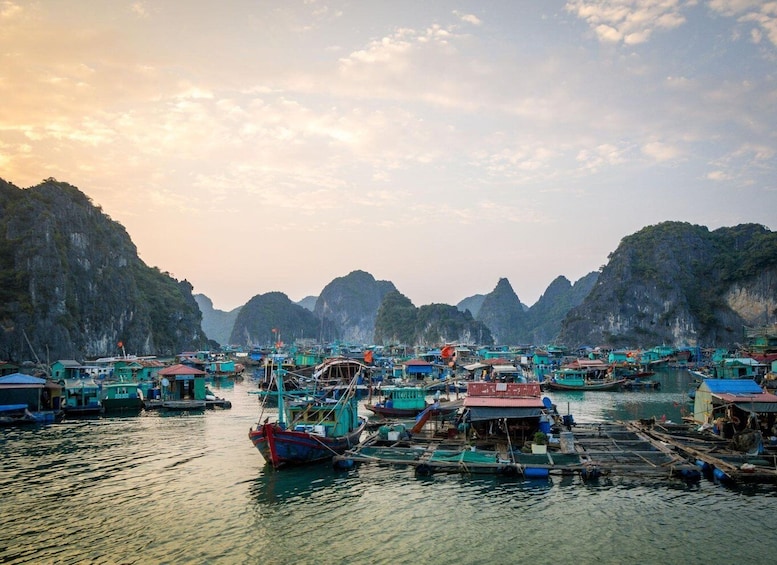 Un village de pêcheurs situé sur la côte, où de nombreux bateaux sont amarrés dans des eaux calmes, le tout étant entouré d’imposantes falaises calcaires. 5