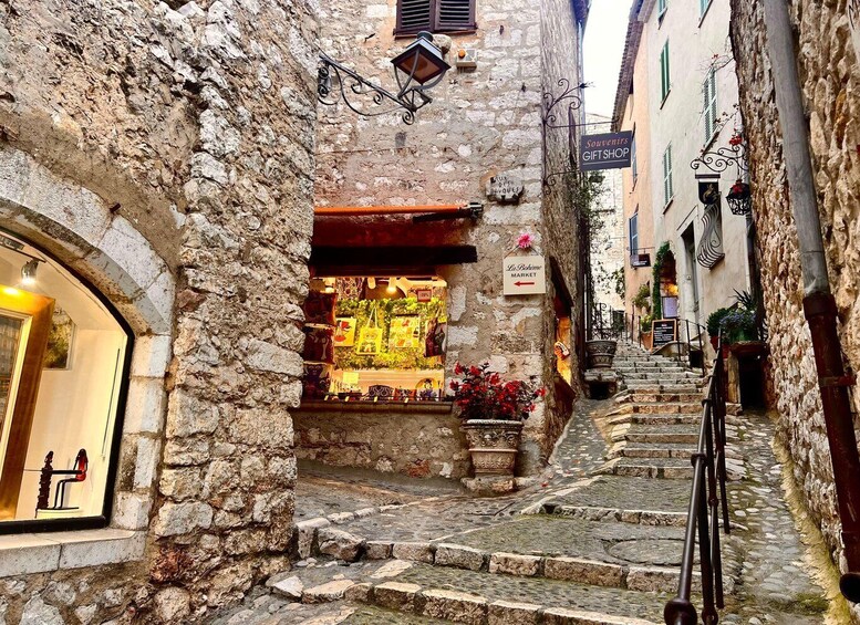 A narrow stone street with a market stall and a gift shop. 5