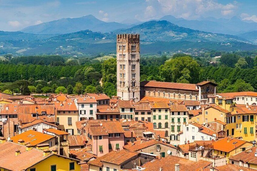 A town with colorful buildings, a prominent tower, and a mountainous backdrop. 4