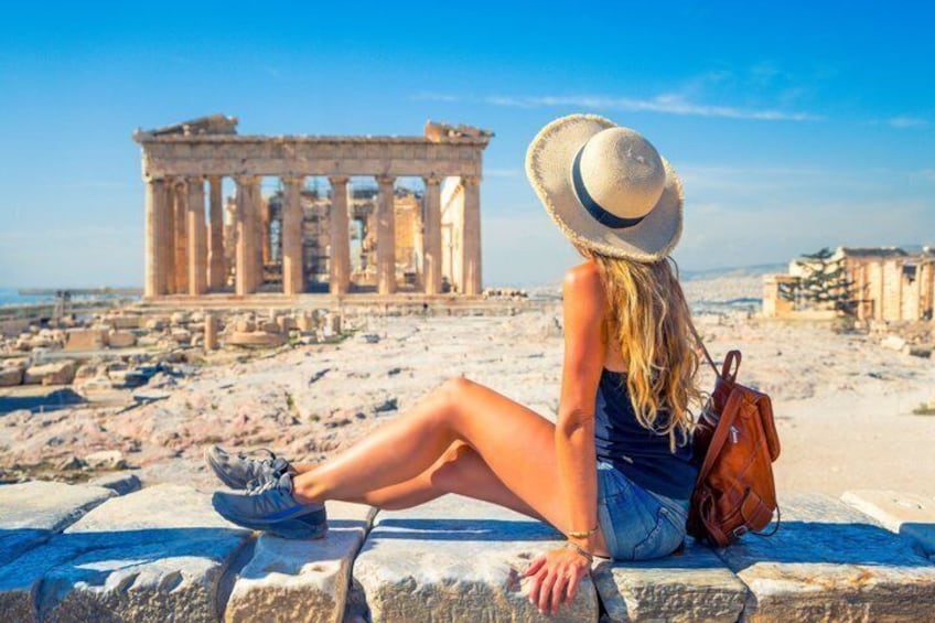 A person sitting on stone steps with a historical building in the background. 1