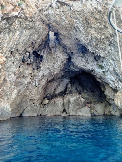 A rocky cave entrance with clear blue water in front. 2