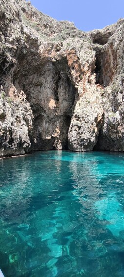 A rocky cliff with clear turquoise water at its base. 5