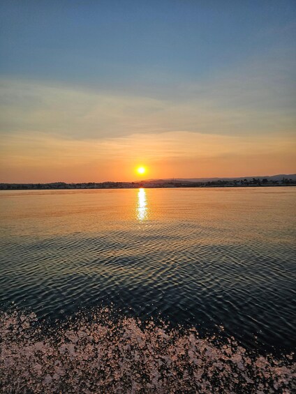A sunset over a calm body of water with a distant shoreline. 5