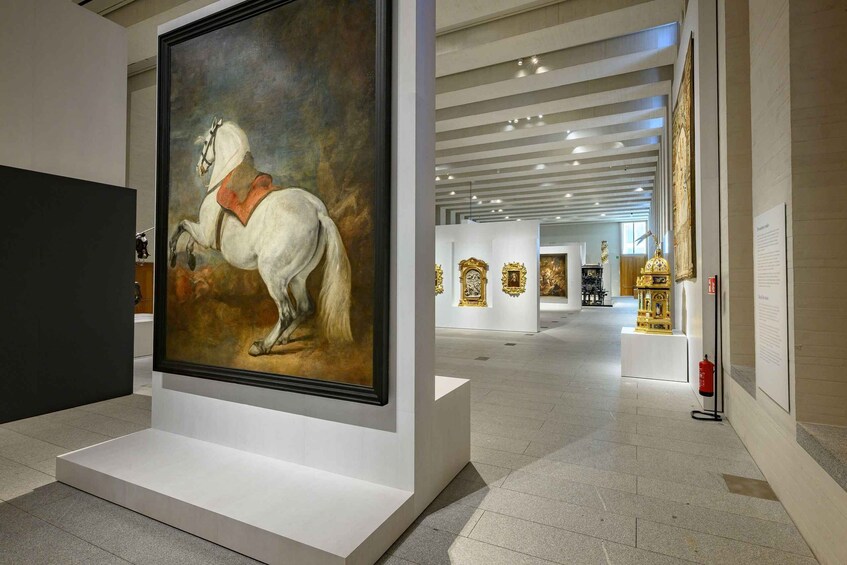 An art gallery with a large painting of a white horse on display. 3