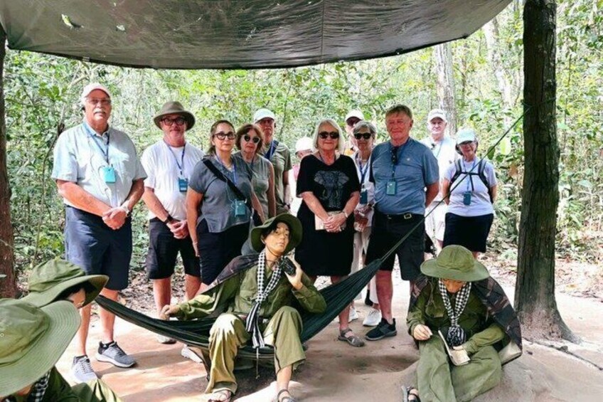 A group of people in a forested area with a hammock and a shaded area. 3