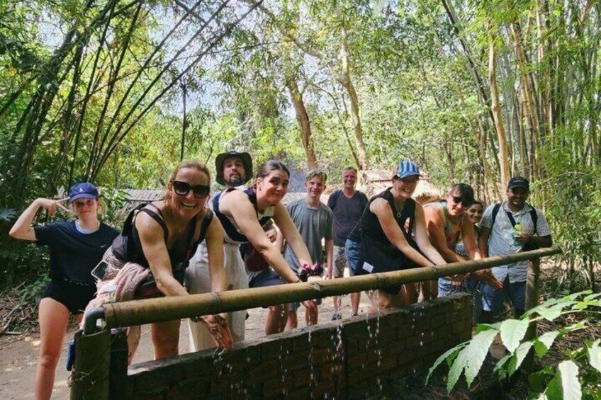 A group of people crossing a wooden bridge in a forested area. 2