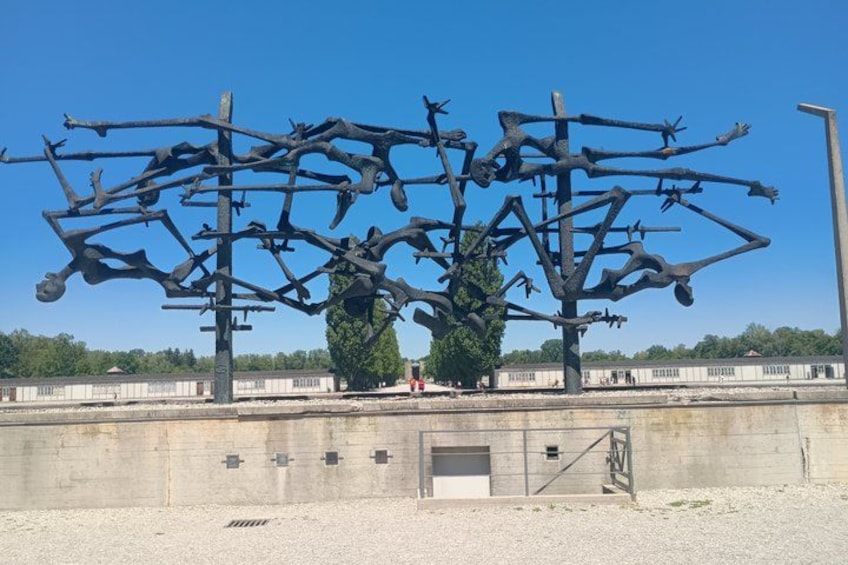 A large metal sculpture with multiple arms and figures, set against a clear blue sky. 5