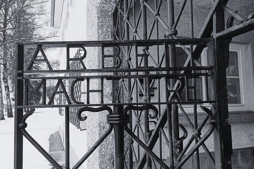 A wrought iron gate with the inscription 'ARBEIT MACHT NICHT' in a black and white photograph. 4