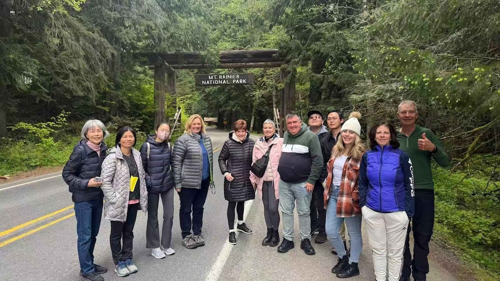 A group of people standing in front of a sign that reads 'Mt. Rainier National Park.' 2