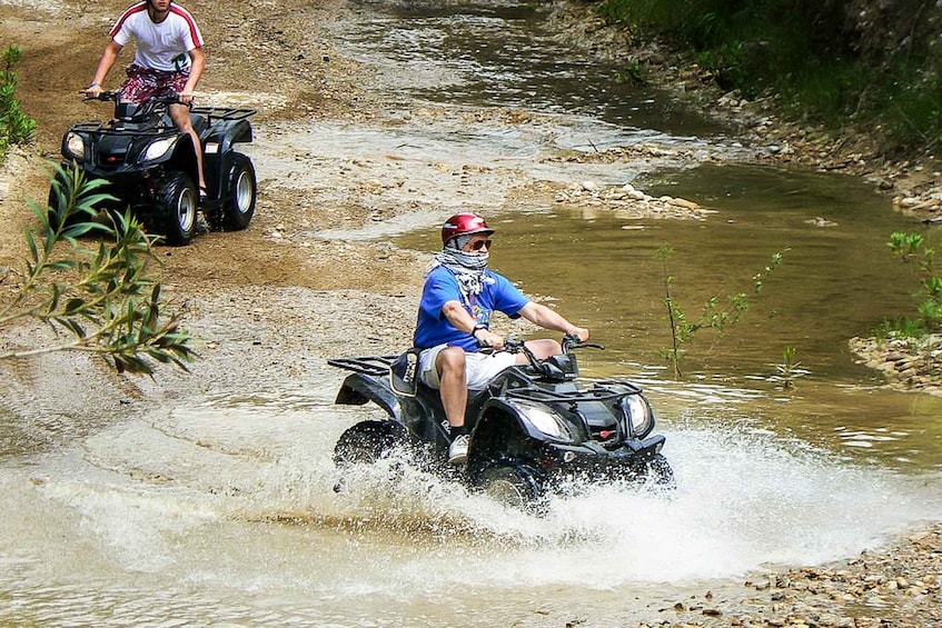 A person riding an ATV through a shallow stream. 3