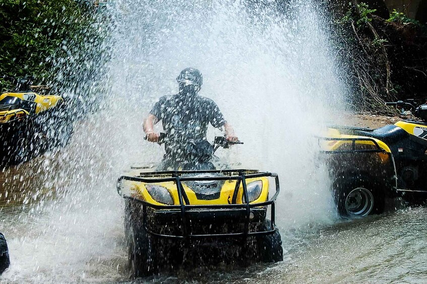 A person in a yellow and black ATV being sprayed with water. 1