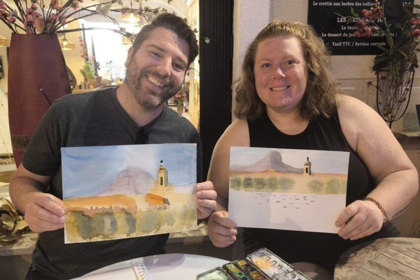 Two people holding watercolor paintings of landscapes. 1