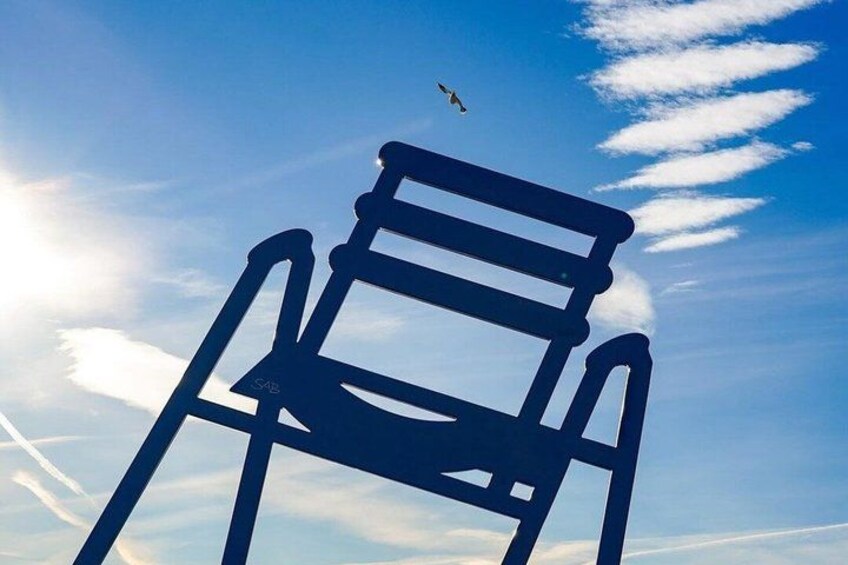 A chair against a clear sky with a bird flying above. 4