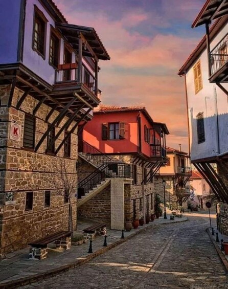 A cobblestone street lined with traditional buildings featuring stone facades and wooden balconies. 1