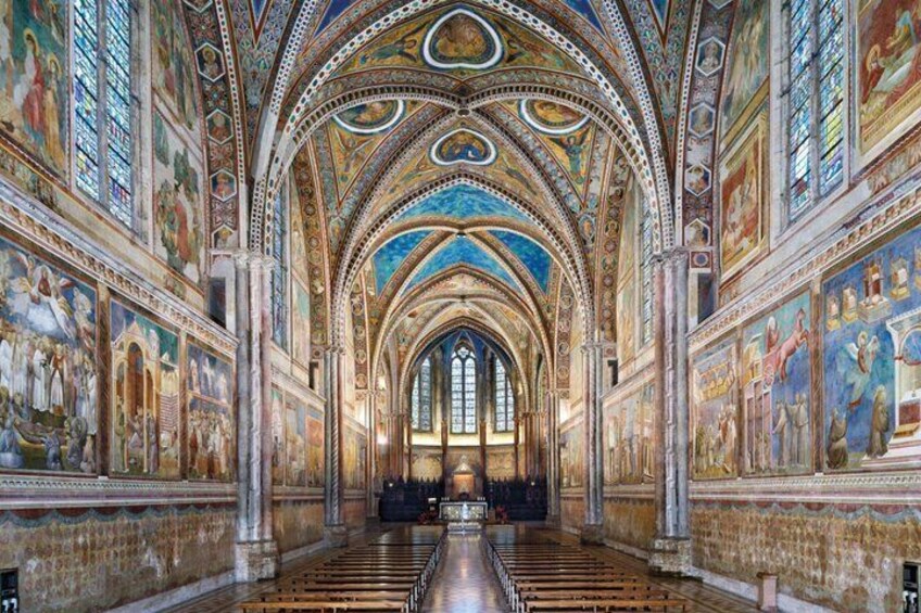 A cathedral interior with high vaulted ceilings, detailed frescoes, and rows of pews. 2