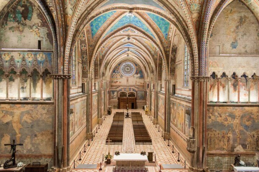 A cathedral interior with arched ceilings, a central aisle, and detailed wall paintings. 3