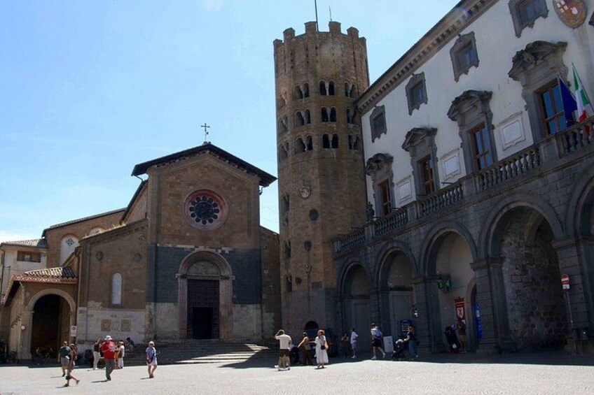 A historic square with a church, a tall tower, and a building with arched windows. 2