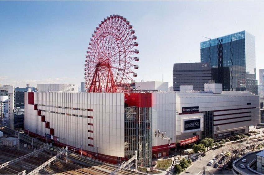 A modern building with a large red Ferris wheel, a cinema, and a glass skyscraper in the background. 4