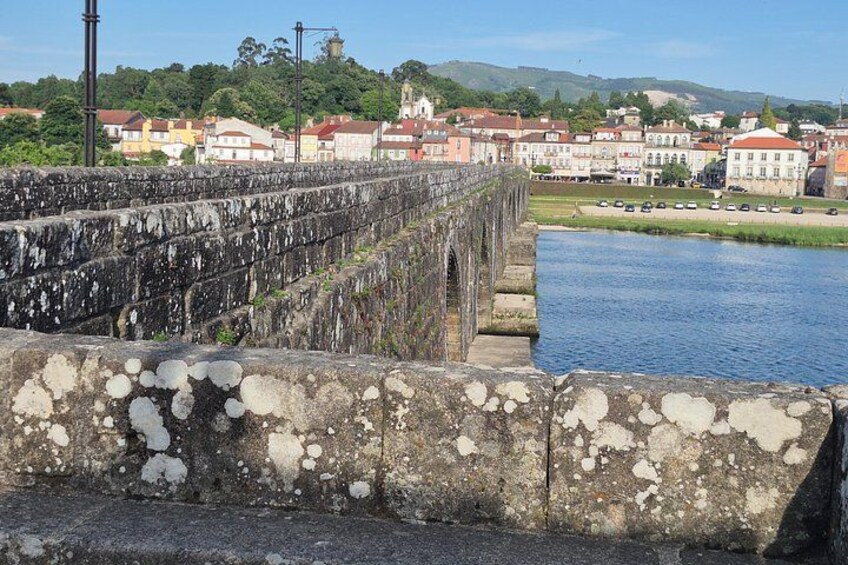 A stone bridge over a river with buildings in the background. 2