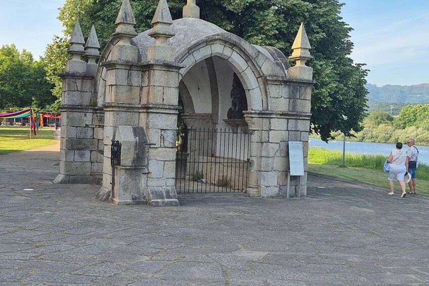 A stone archway with a statue, a metal gate, and a signboard. 4