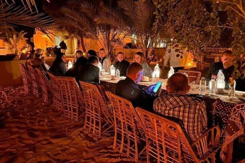 A restaurant with wicker chairs and tables, people dining, and a warm ambient light. 2