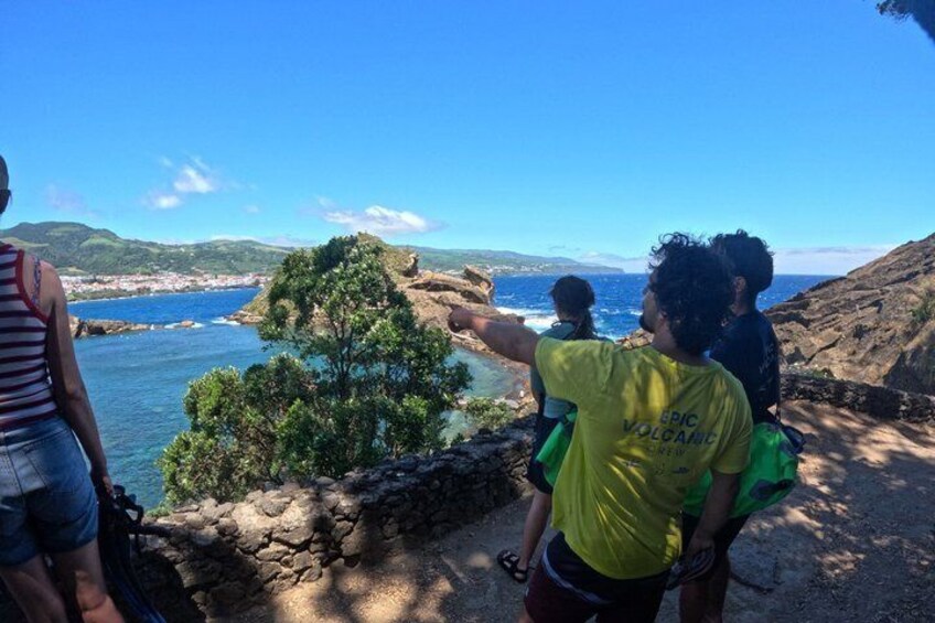 A group of people overlooking a coastal landscape with a view of the sea and distant hills. 3