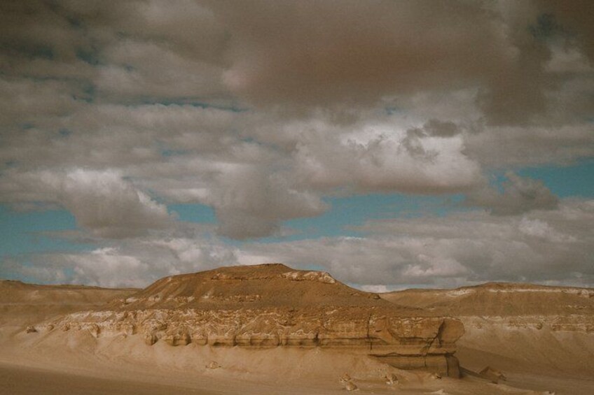 A desert landscape with rolling hills and a cloudy sky. 3