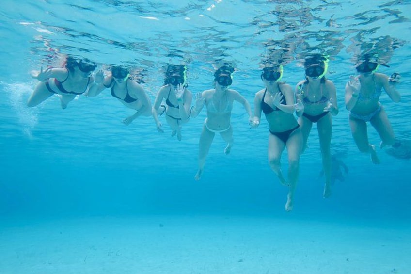 A group of people swimming underwater in a pool. 4
